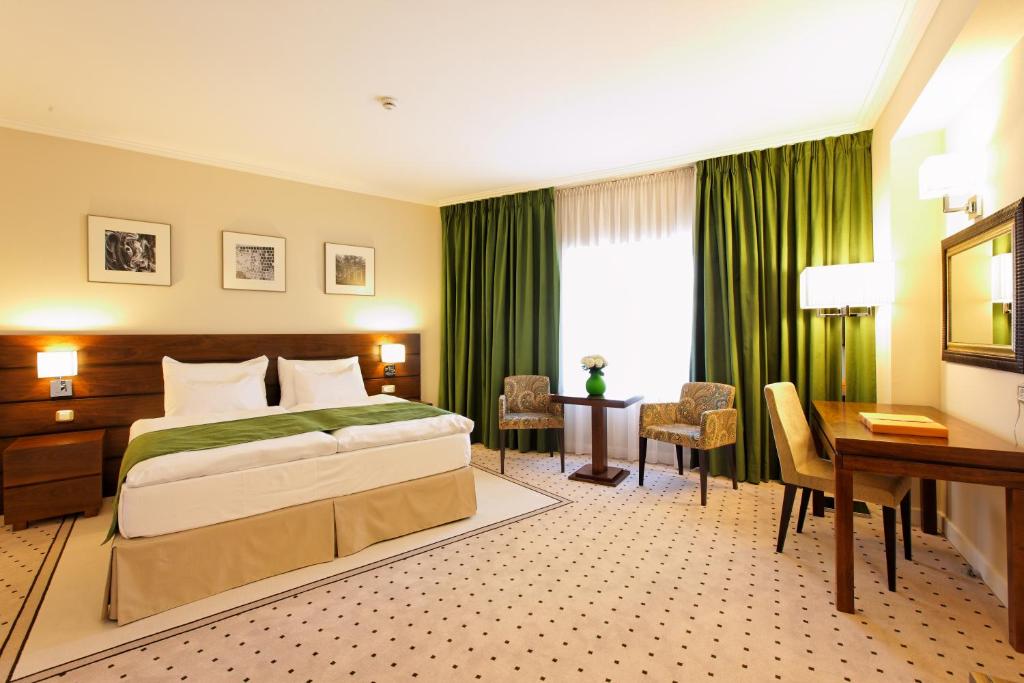 a hotel room with a bed and a desk and a desk at Capital Plaza Hotel in Bucharest