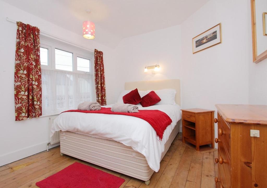 Un dormitorio con una cama con almohadas rojas y una ventana en Large Cosy House Ideal for Corporate Lets, en Andover