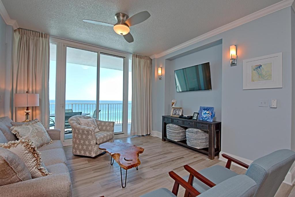 ein Wohnzimmer mit einem Sofa, Stühlen und einem TV in der Unterkunft Lighthouse 714 in Gulf Shores