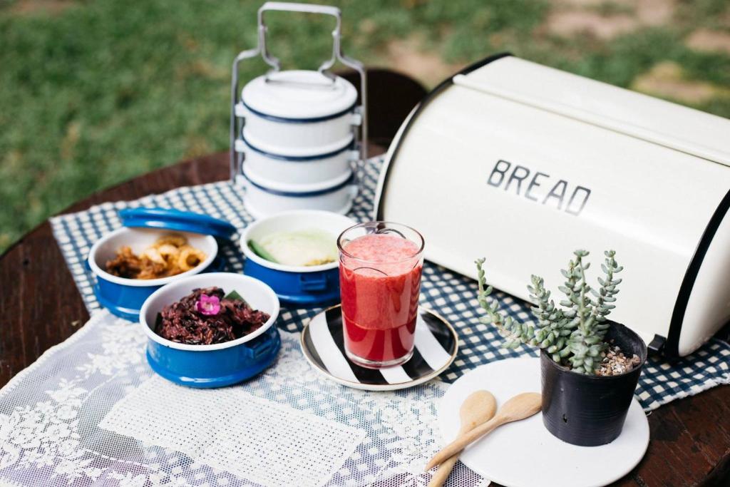 An outdoor picnic-style breakfast spread with drinks, bowls, and bread.