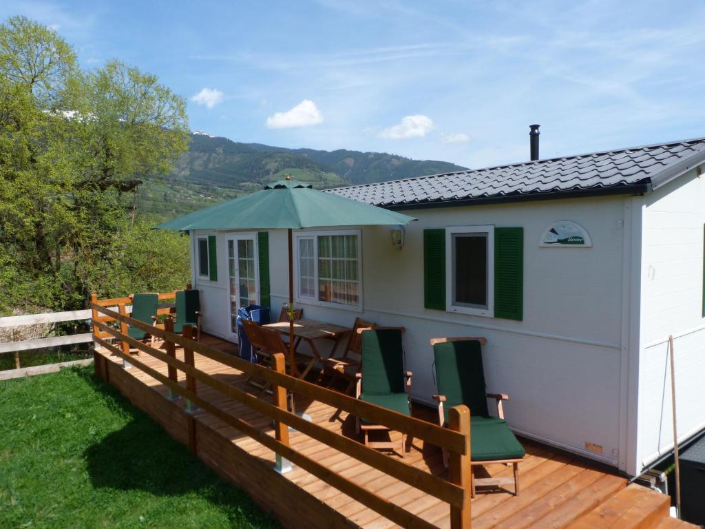 a house with a deck with a table and chairs at Mobilheim Seezauber in Uttendorf