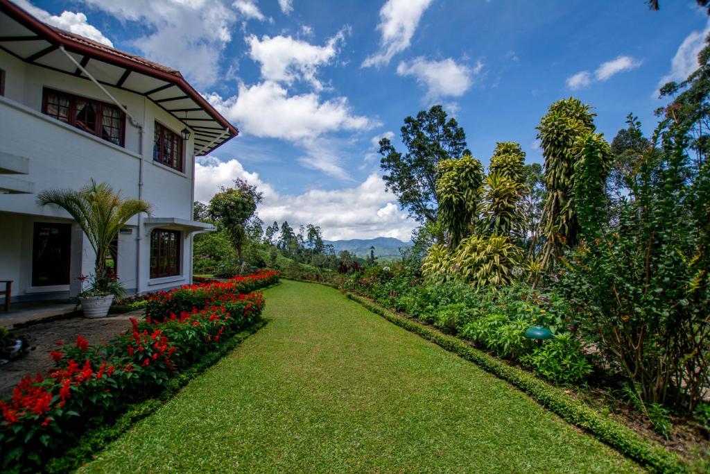 a garden in front of a house with red flowers at Governor's Mansion in Hatton