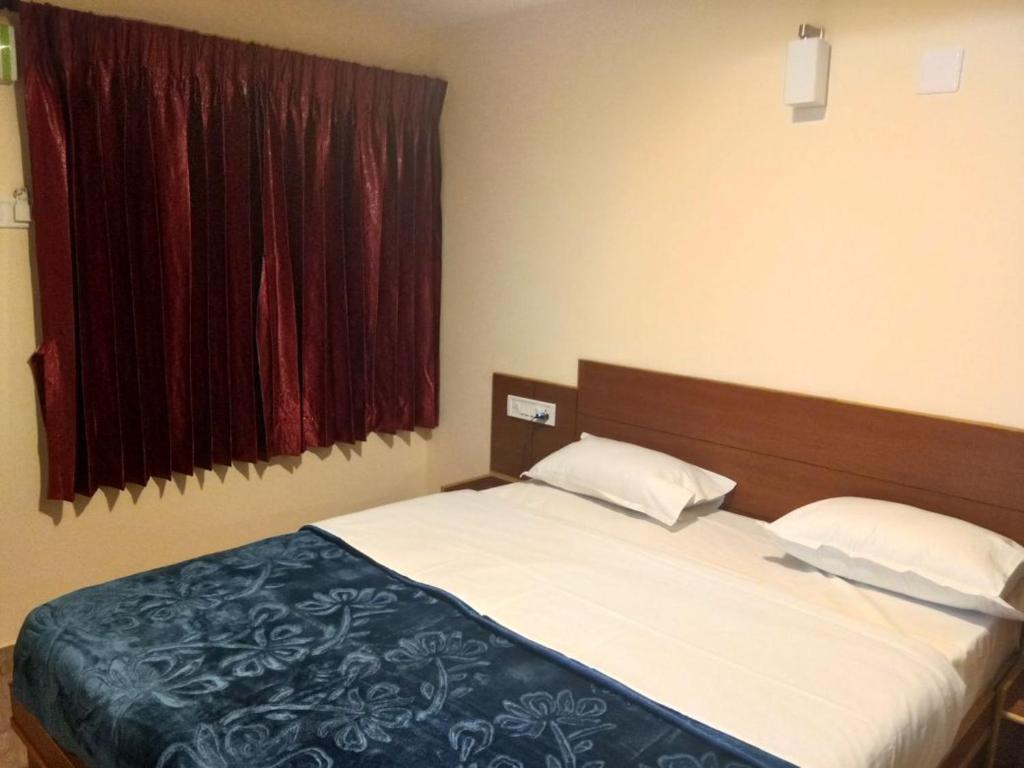 1 dormitorio con cama y ventana en Nook Residency, en Ooty