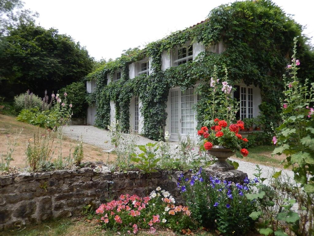 uma casa coberta de hera com flores num jardim em Le Petit Massigny em Velluire