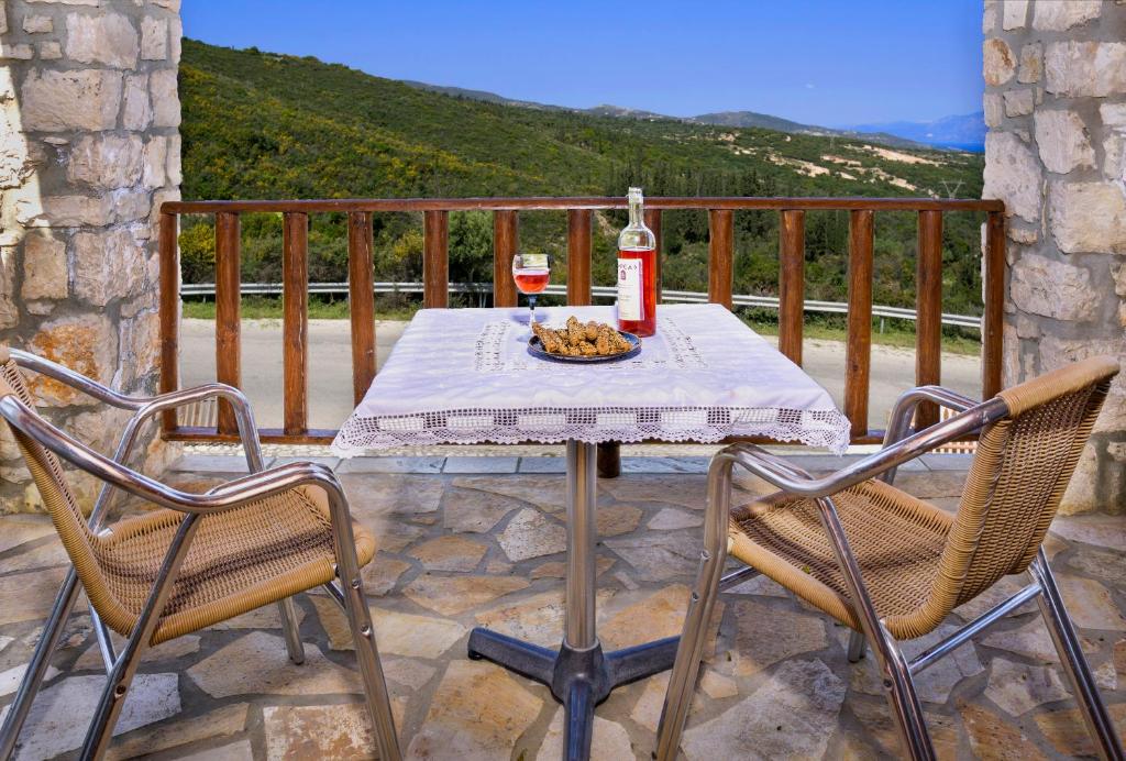 a table with a bottle of wine and two chairs at Nireas : Stone Villa in Zakynthos