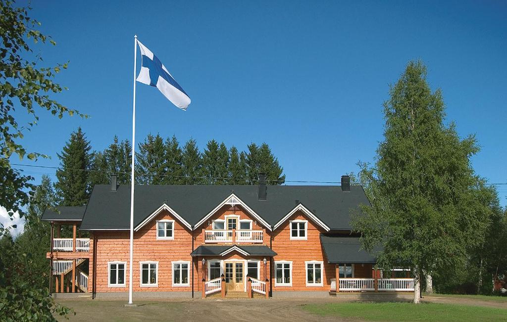 una bandiera battente di fronte a una grande casa di Guest House Haapaniemen Hirsikartano a Iisalmi