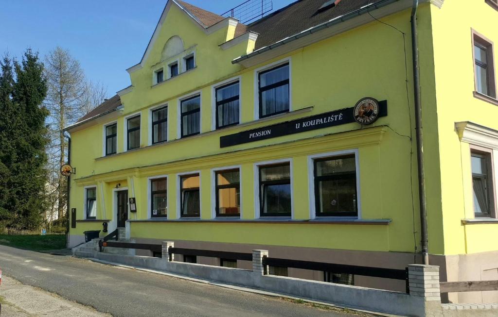 ein gelbes Gebäude an der Straßenseite in der Unterkunft Pension U Koupaliště in Tisá