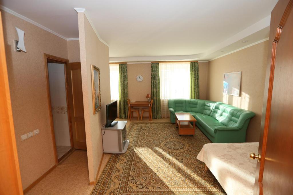 a living room with a green couch and a television at Venecia in Usinsk