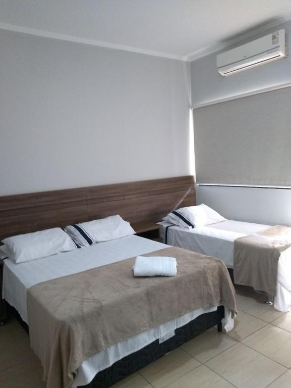 a hotel room with two beds with white sheets at Flex Hotel in Três Lagoas