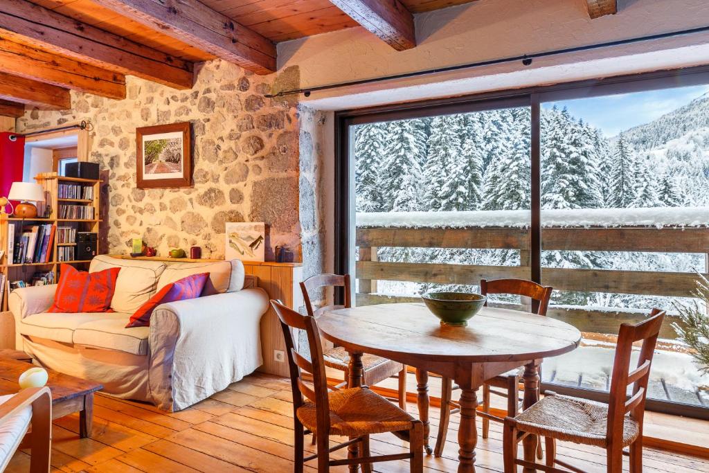 a living room with a table and a large window at Maison de caractère dans la chartreuse in Saint-Pierre-de-Chartreuse