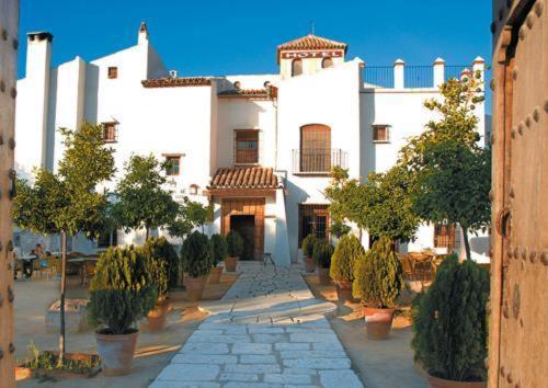 un grand bâtiment blanc avec des arbres devant lui dans l'établissement Posada de Jose Mª El Tempranillo, à Alameda