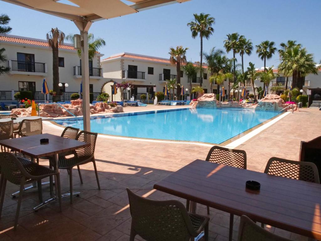 a swimming pool with tables and chairs in a resort at Loutsiana Deluxe Apts in Ayia Napa