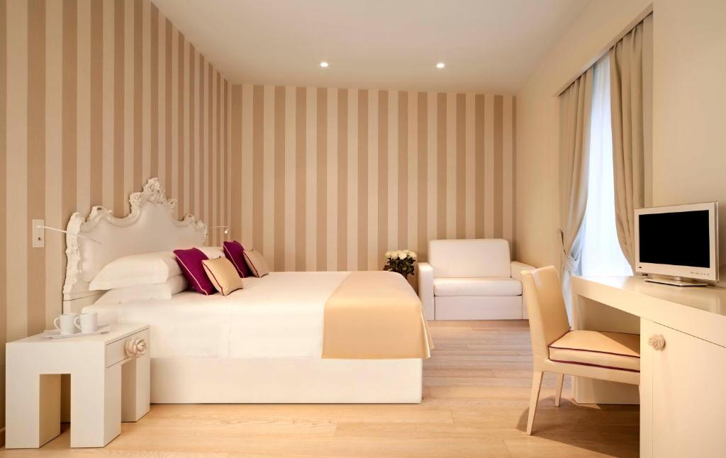 a bedroom with a bed and a desk and a television at Rooms Milano Duomo in Milan