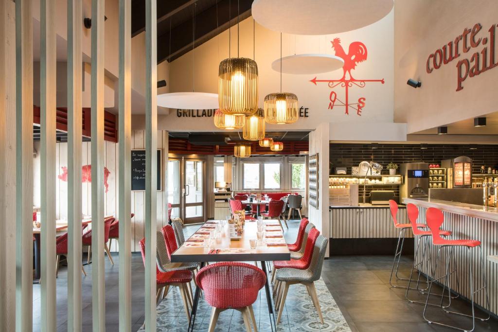 a dining room with a table and red chairs at ibis Reims Tinqueux in Reims