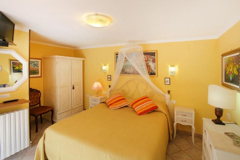 a yellow bedroom with a large bed with orange pillows at Primettahouse in San Gimignano