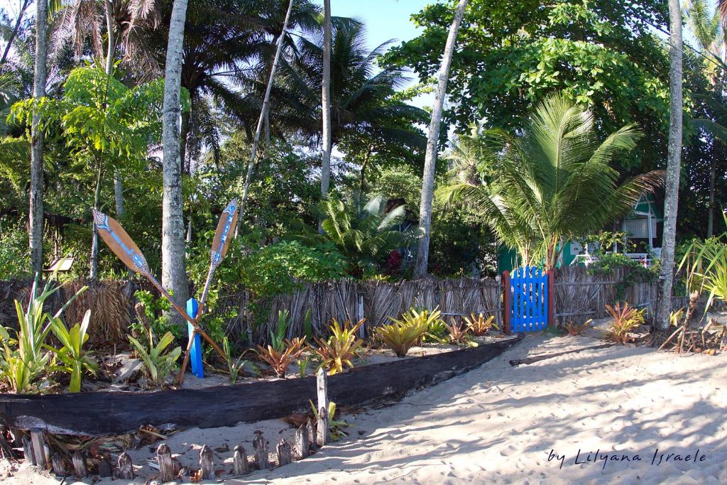 een tuin met palmbomen en een blauwe poort bij Pousada Vila Sereia in Ilha de Boipeba