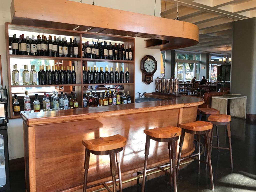a bar with wooden stools and bottles of wine at Hotel Boutique Raíces in Curicó