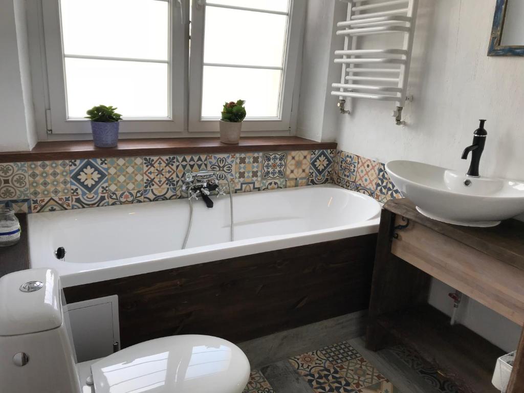 a bathroom with a tub and a sink and a toilet at Apartament Do Zobaczenia Olsztyn Miejsce Nieidealne in Olsztyn