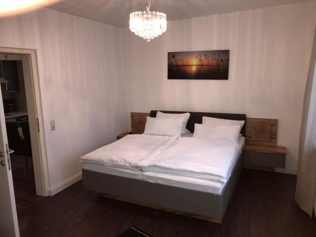 a bedroom with a bed with white sheets and a chandelier at Fachwerkhaus in der Altstadt in Lüneburg