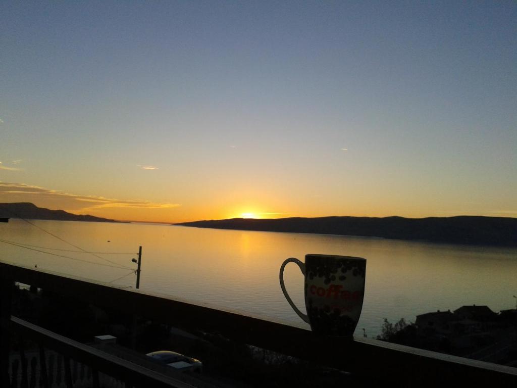 uma chávena de café sentada numa varanda com o pôr-do-sol em Natalie em Senj