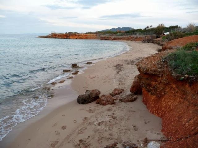 a sandy beach with rocks and the ocean at Sunshine's house near the beach, 10 min from the airport in Artemida