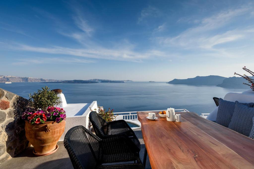 a wooden table on a balcony with a view of the ocean at Strogili in Oia