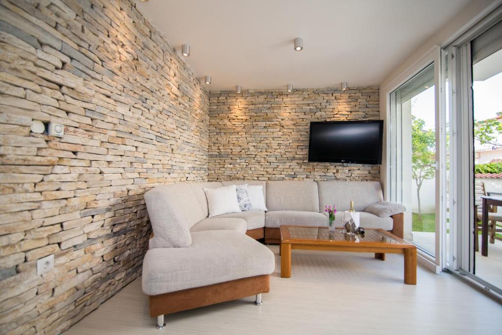a living room with a couch and a tv on a brick wall at Apartments Lili Flora in Zadar