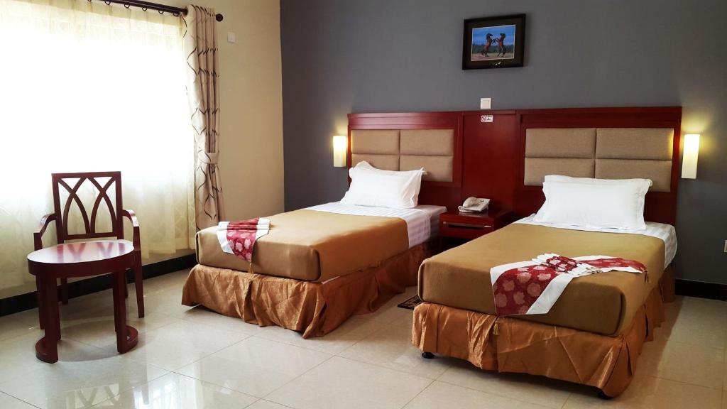Pokój hotelowy z 2 łóżkami i krzesłem w obiekcie Northern Rock Hotel w mieście Mpika