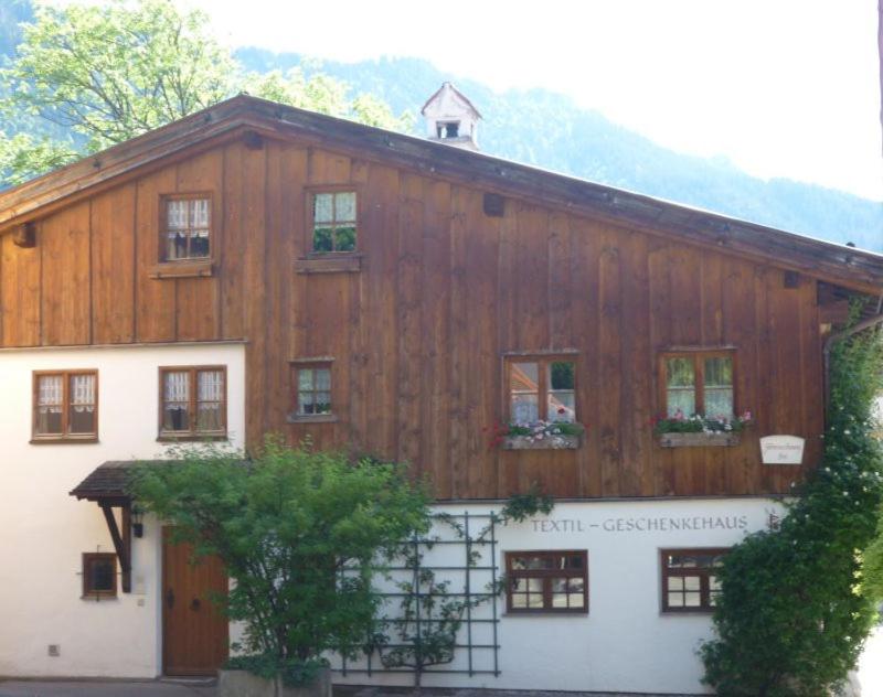 ein großes Holzgebäude mit Fenstern und einem Baum in der Unterkunft City Apartment in Oberammergau
