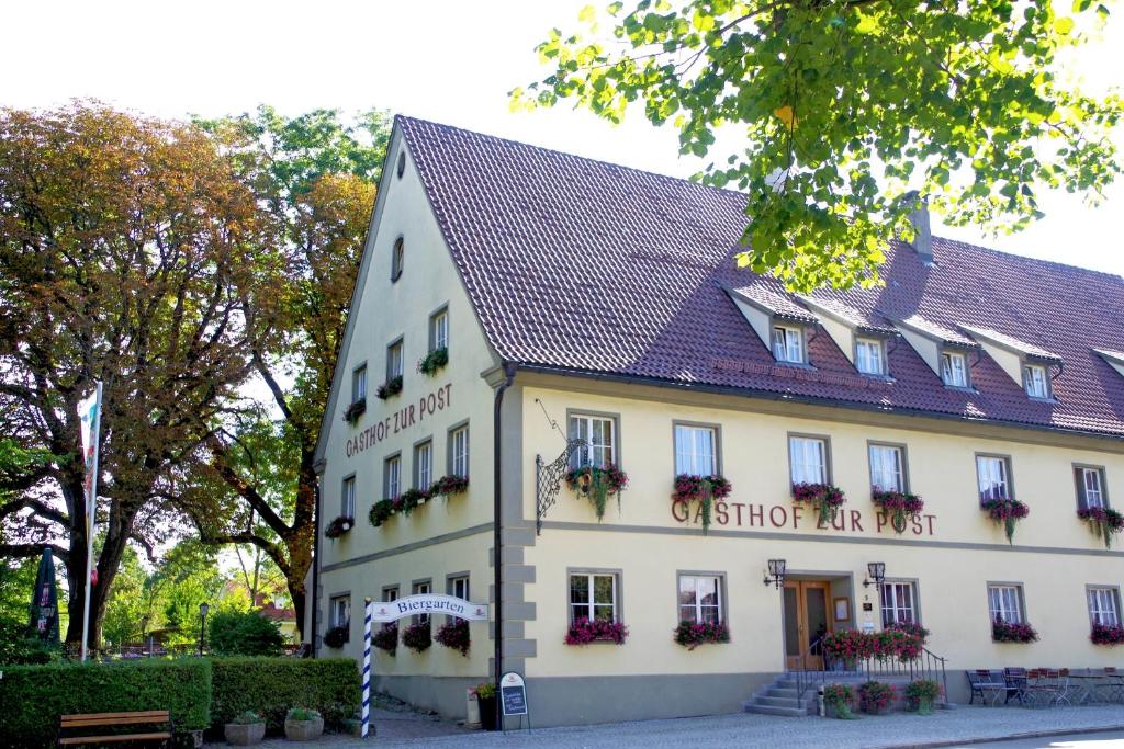 a white building with a sign on it at Hotel Gasthof zur Post in Wolfegg