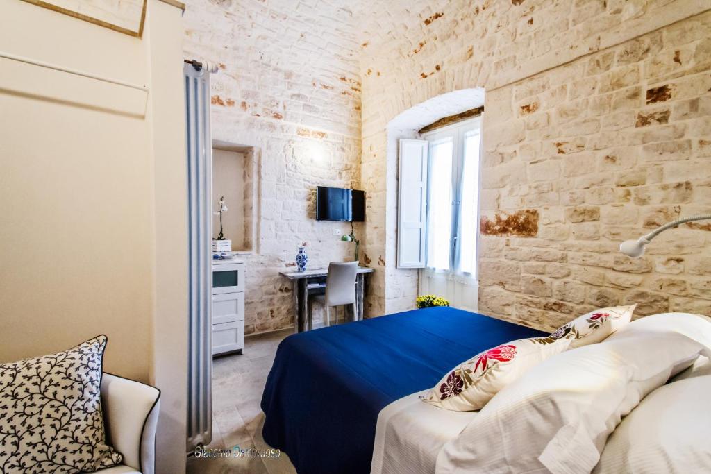 a bedroom with a blue bed and a stone wall at Borgo Noci in Noci