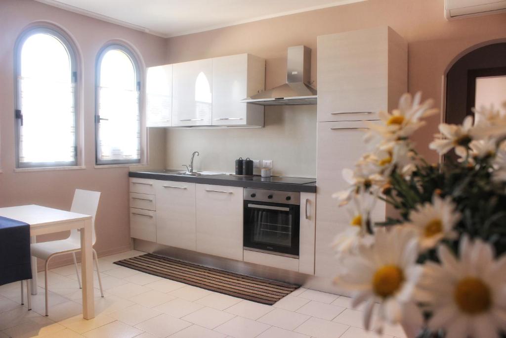 a kitchen with white cabinets and a table with a flower at Villa Carina in Massa