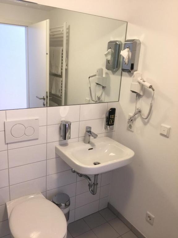 a white bathroom with a toilet and a sink at Hotel Central Hannover in Hannover