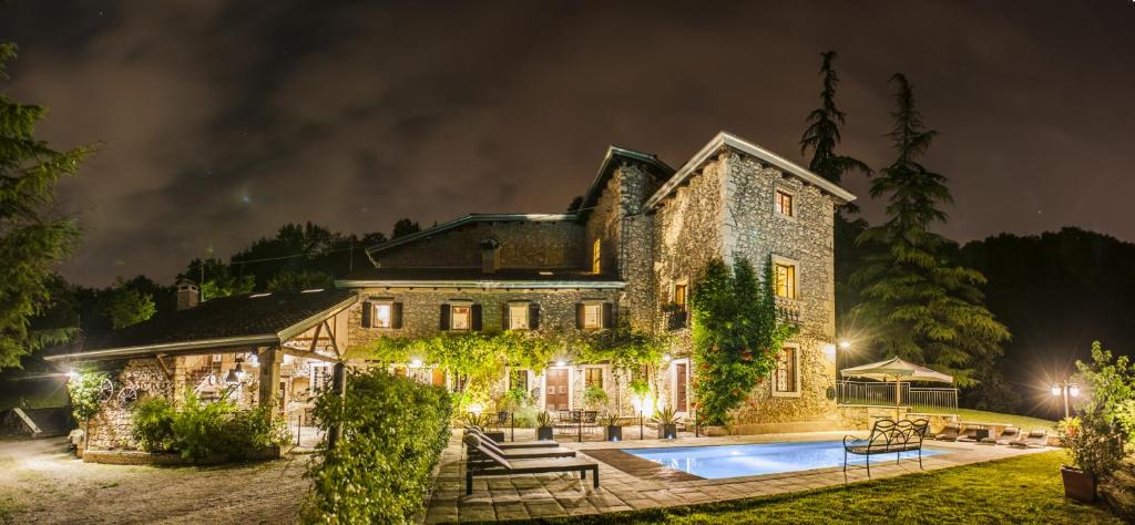 Monte San Lorenzo的住宿－Villa Sibilla Il Giardino Di Sibilla With Pool，一座大型石头房子,晚上设有游泳池