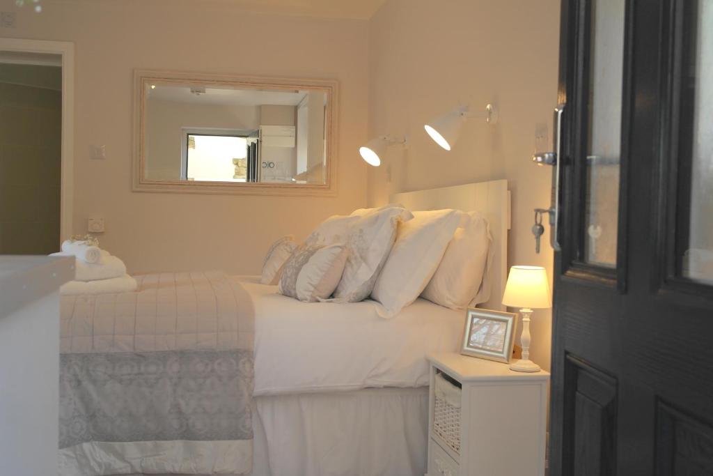 a bedroom with a bed with white pillows and a mirror at Ashford house 'The Snug' private hot tub in Fylingthorpe