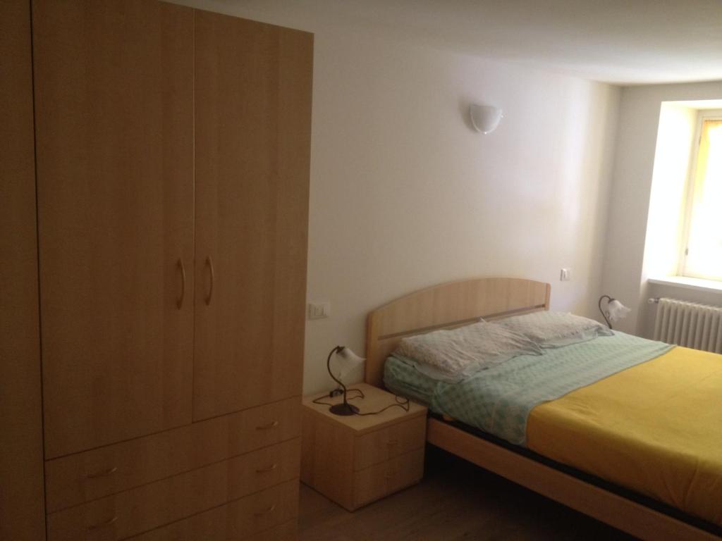a bedroom with a bed and a dresser with a lamp at Appartamento Lavarone in Lavarone