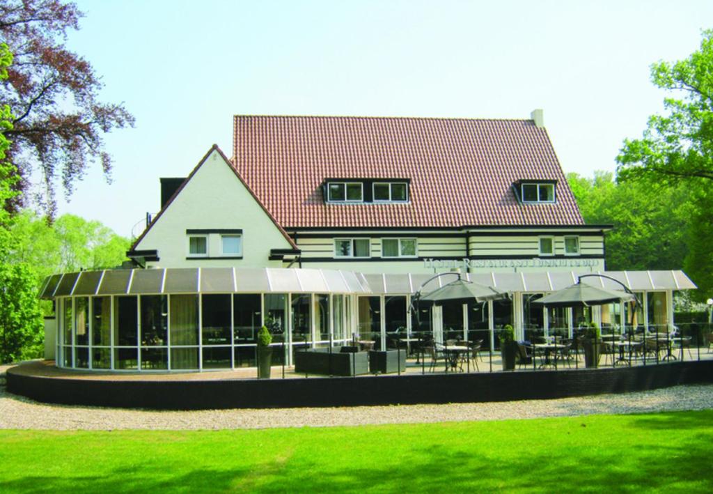 Fletcher Hotel Restaurant Dinkeloord في Beuningen: منزل كبير أمامه طاولات وكراسي
