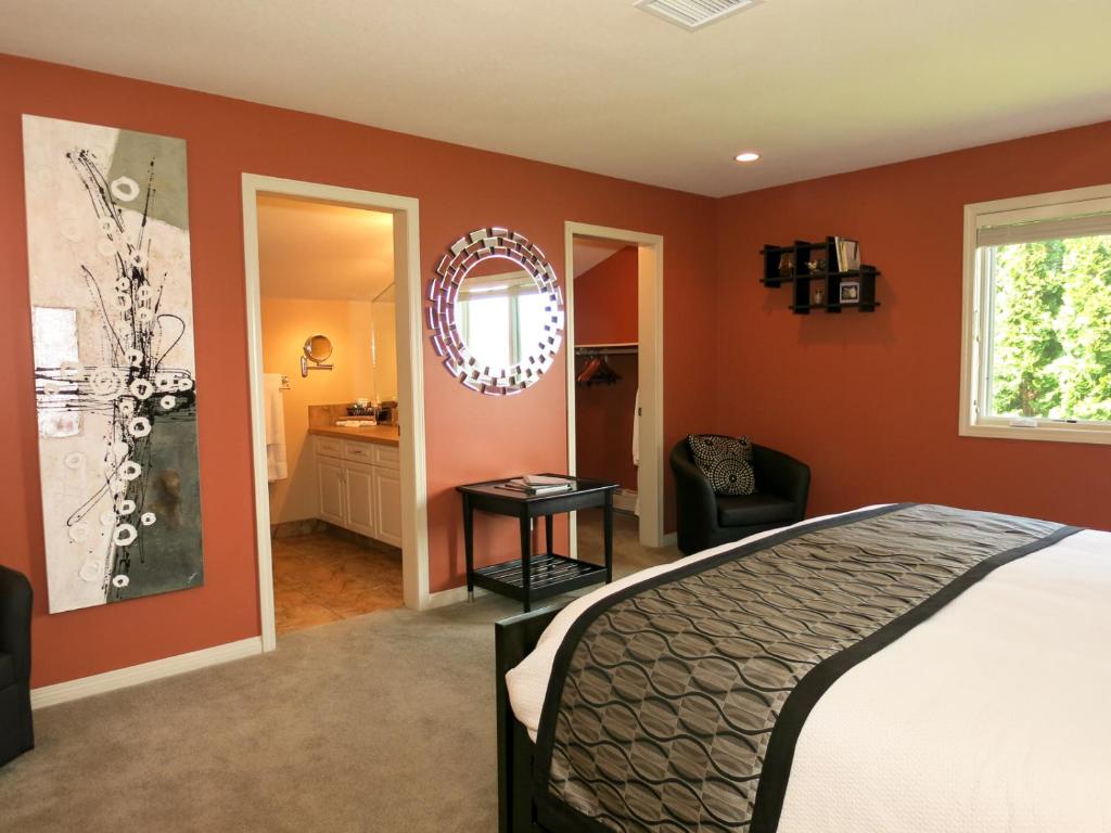 Schlafzimmer mit orangefarbenen Wänden, einem Bett und einem Spiegel in der Unterkunft A View of the Lake B & B in West Kelowna