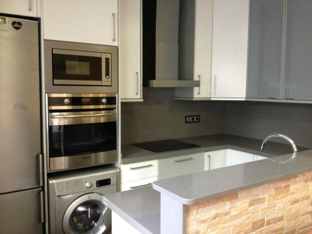 kuchnia z białymi szafkami i urządzeniem ze stali nierdzewnej w obiekcie Apartamento Cala Blanca w mieście Gandía