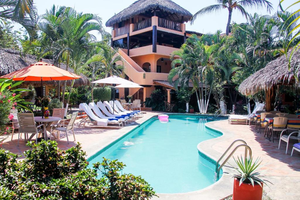 een resort met een zwembad en stoelen en een gebouw bij Hotel Casamar Suites in Puerto Escondido
