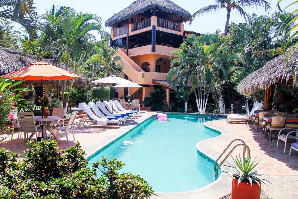 Un complejo con piscina y sillas y un edificio. en Hotel Casamar Suites, en Puerto Escondido