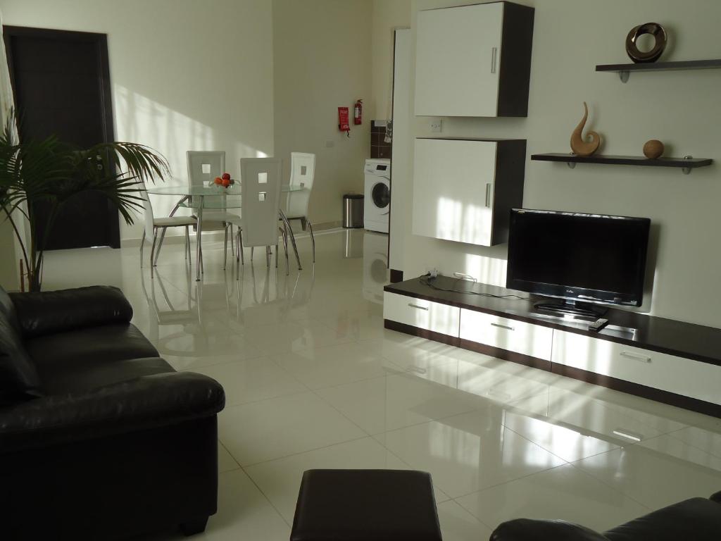 sala de estar con sofá y TV de pantalla plana en Shamrock Flats, en Mellieħa