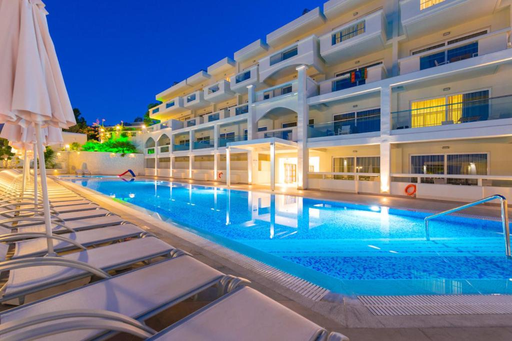 a swimming pool in front of a building at night at Lindos White Hotel & Suites in Líndos