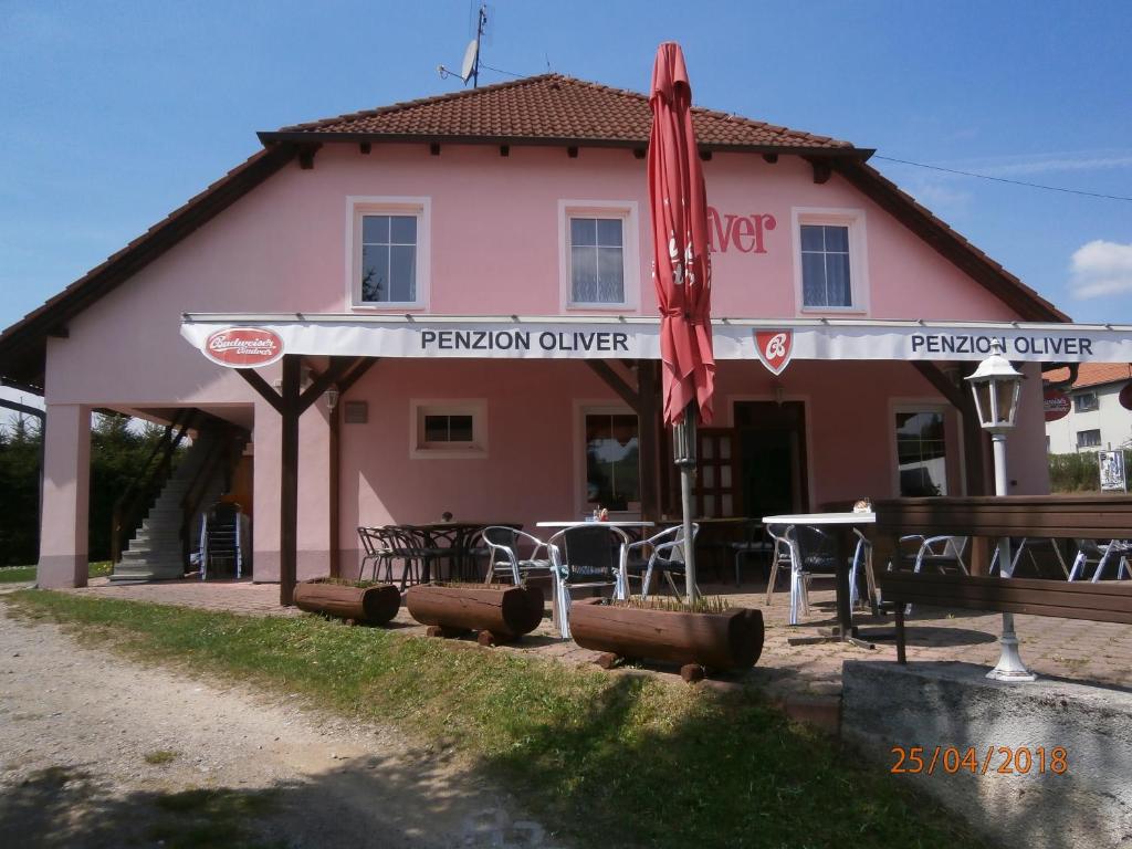 a pink building with a table and a red umbrella at Penzion Oliver in Horní Planá