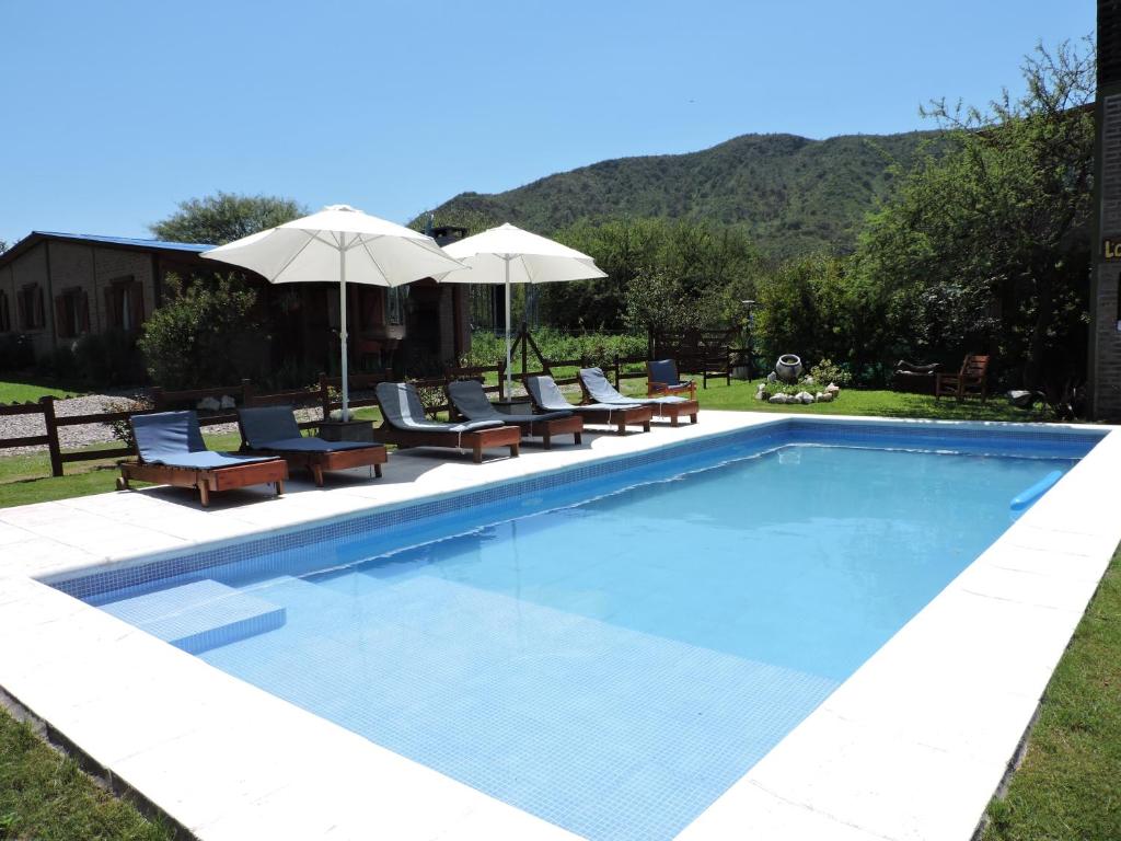 ein Swimmingpool mit Stühlen und Sonnenschirmen in der Unterkunft CABAÑAS LOS COCKERS in Villa General Belgrano