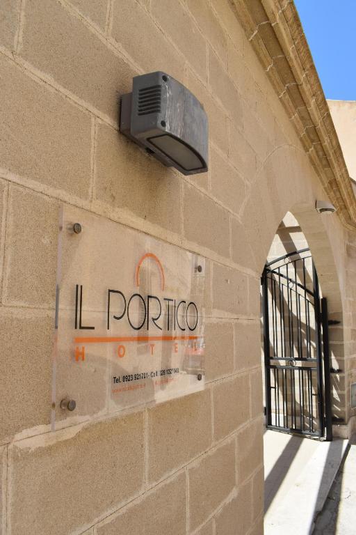 un cartello sul lato di un edificio con una luce di Hotel Il Portico a Favignana
