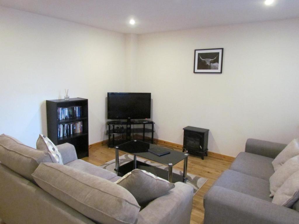 a living room with two couches and a flat screen tv at Farraline Court in Inverness