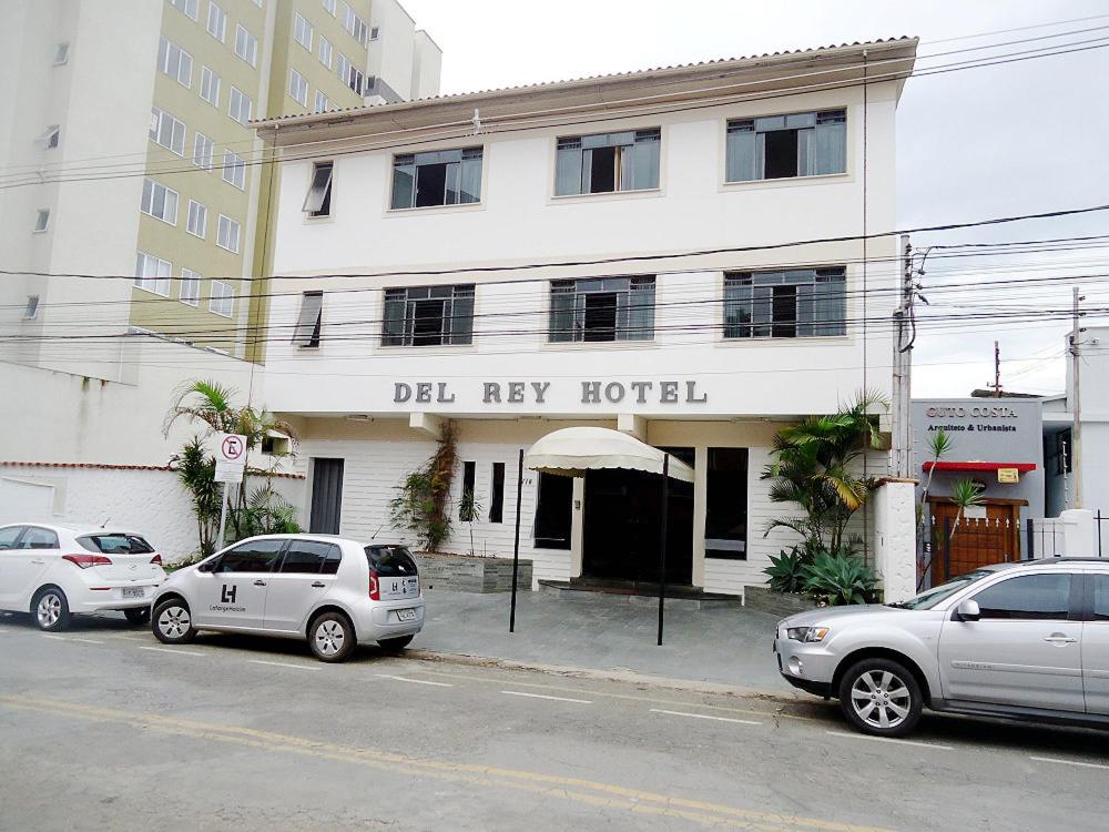 a white building with cars parked in front of it at Del Rey Hotel in Barbacena