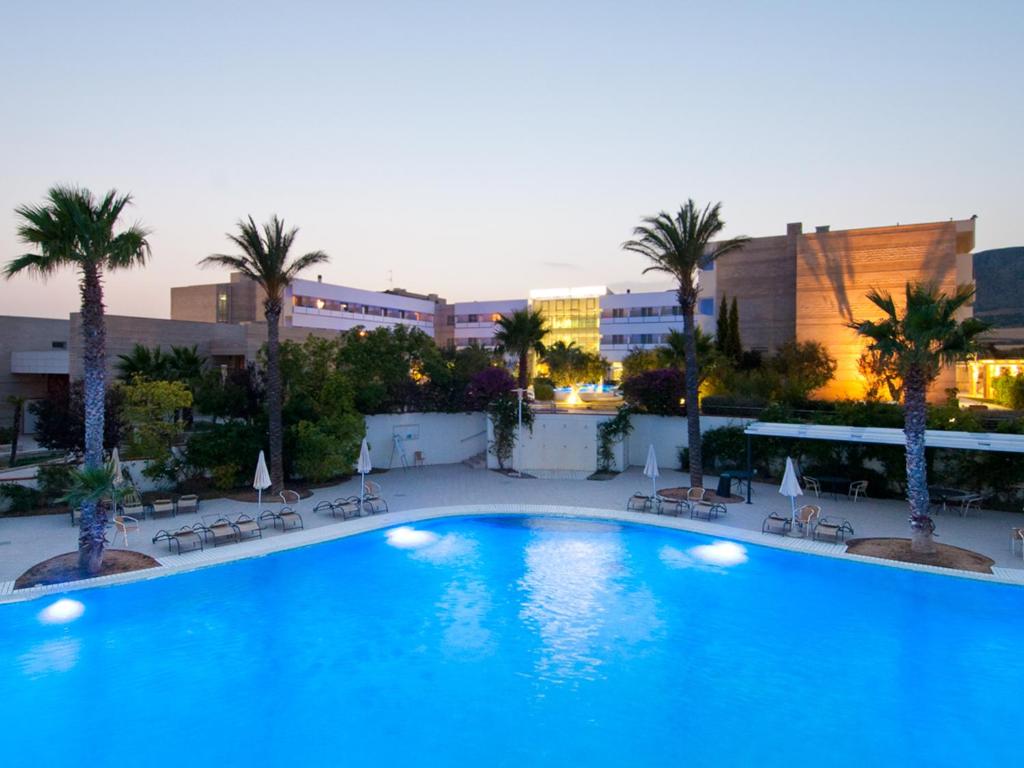 a large blue swimming pool with palm trees and buildings at Regiohotel Manfredi in Manfredonia