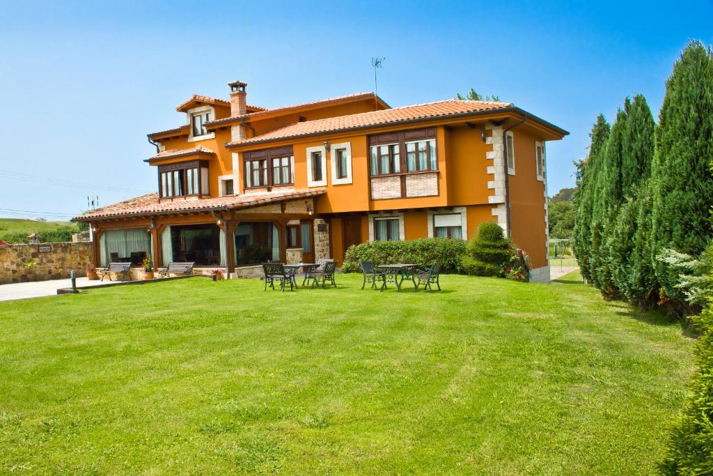 une grande maison avec une pelouse devant elle dans l'établissement Hospedaje Granada, à San Vicente de la Barquera
